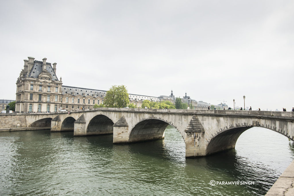 Walking across the Seine River towards the Louvre Museum.